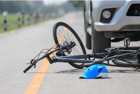 bicycle laying in the road in front of a car